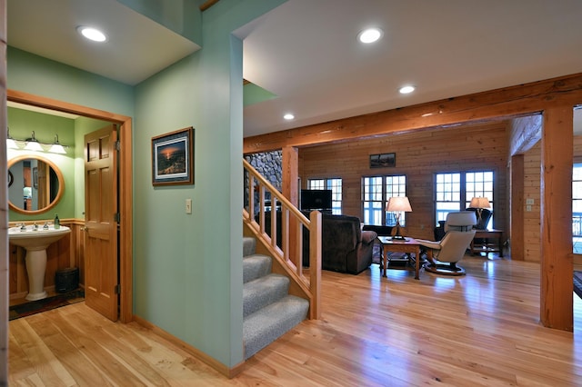 hallway with sink, wooden walls, and light wood-type flooring