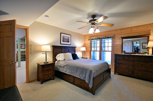 carpeted bedroom featuring ceiling fan and wooden walls