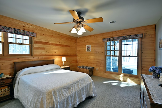 bedroom with multiple windows, wooden walls, and carpet