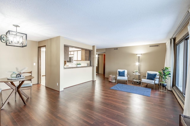 sitting room featuring a baseboard radiator, visible vents, dark wood finished floors, and a textured ceiling