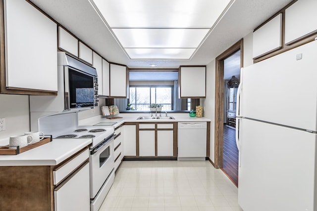 kitchen with a sink, white appliances, white cabinets, and light countertops