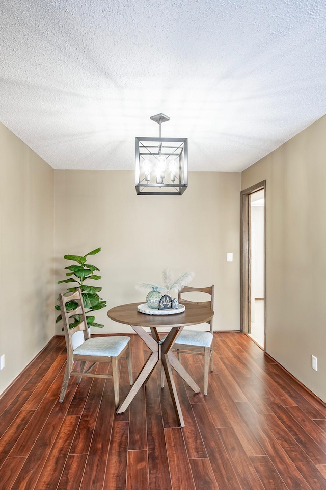 dining space with a notable chandelier, a textured ceiling, and dark wood-style flooring