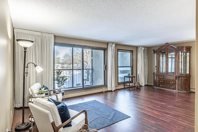 unfurnished living room featuring dark wood-type flooring, a baseboard heating unit, and a textured ceiling