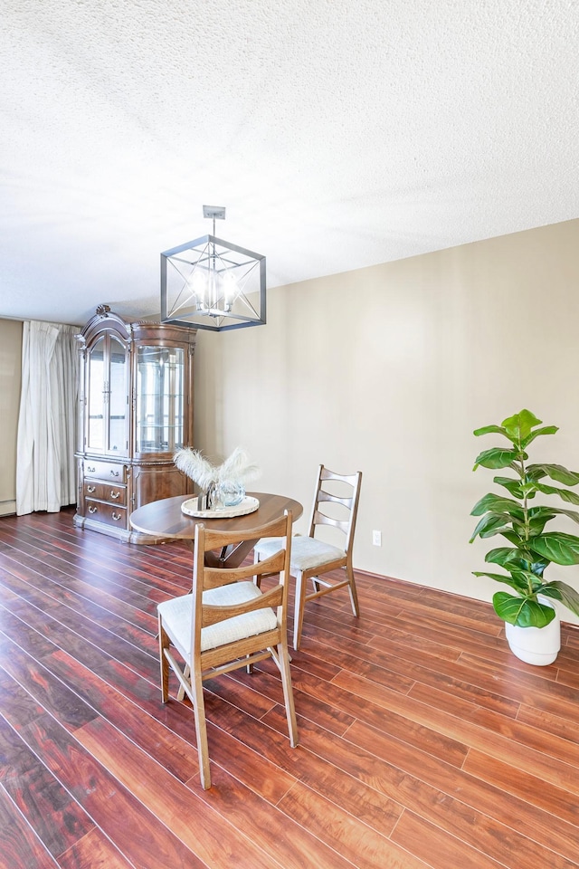 dining space with a textured ceiling, wood finished floors, and a chandelier