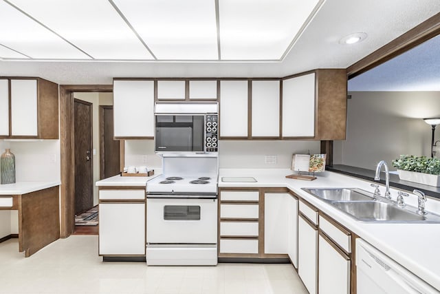 kitchen with light countertops, white appliances, a sink, and white cabinets