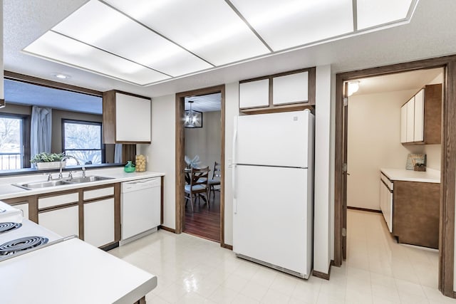 kitchen with white appliances, white cabinets, light countertops, light floors, and a sink