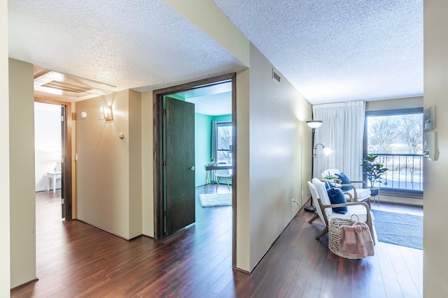 corridor featuring dark wood-style floors, visible vents, and a textured ceiling