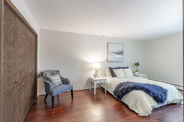 bedroom featuring a baseboard radiator, a textured ceiling, dark wood finished floors, and a closet