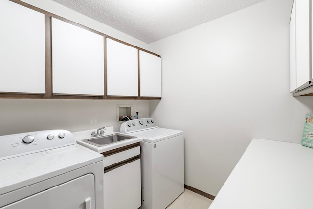 laundry area featuring a textured ceiling, a sink, baseboards, cabinet space, and washing machine and clothes dryer