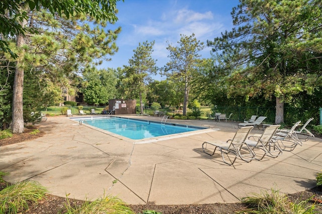 community pool featuring a patio area, fence, and an outdoor structure