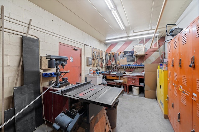 interior space with concrete flooring, a workshop area, and concrete block wall