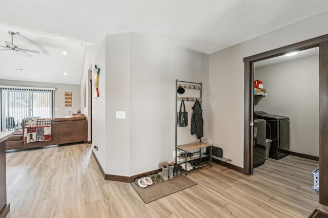 hallway with washing machine and clothes dryer, lofted ceiling, a textured ceiling, and light wood-type flooring