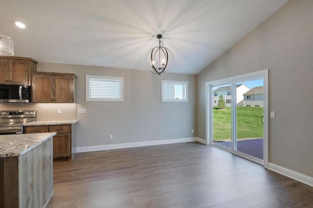 kitchen with plenty of natural light, appliances with stainless steel finishes, decorative light fixtures, and backsplash