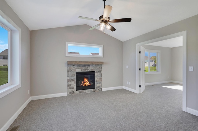 unfurnished living room featuring ceiling fan, lofted ceiling, carpet flooring, and a stone fireplace