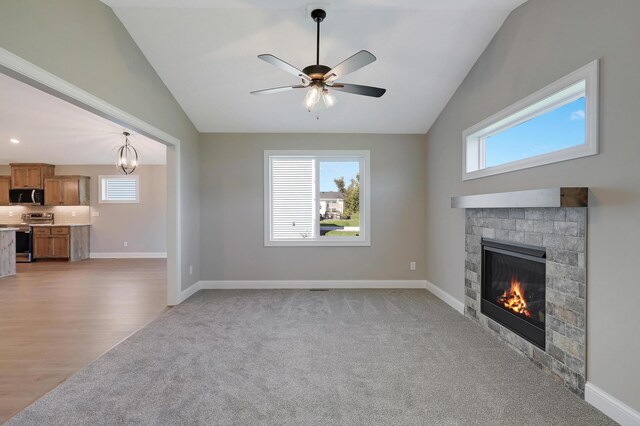 unfurnished living room with lofted ceiling, ceiling fan with notable chandelier, and light colored carpet