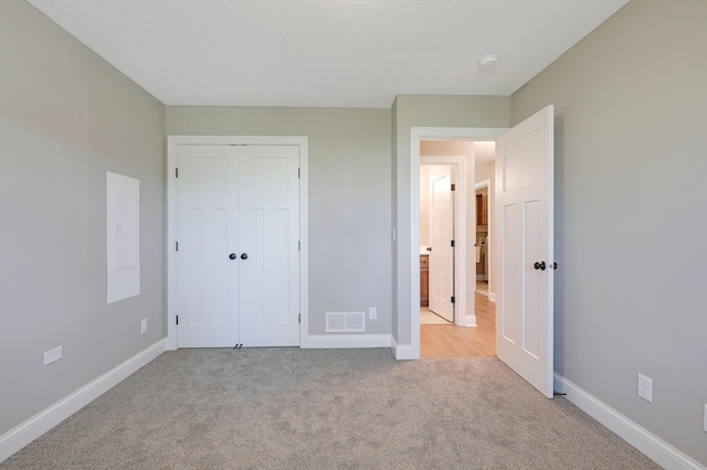 unfurnished bedroom featuring light carpet and a closet