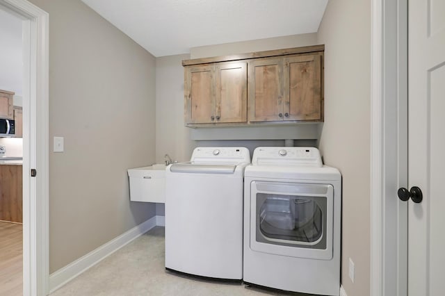 clothes washing area featuring cabinets, washer and clothes dryer, and sink