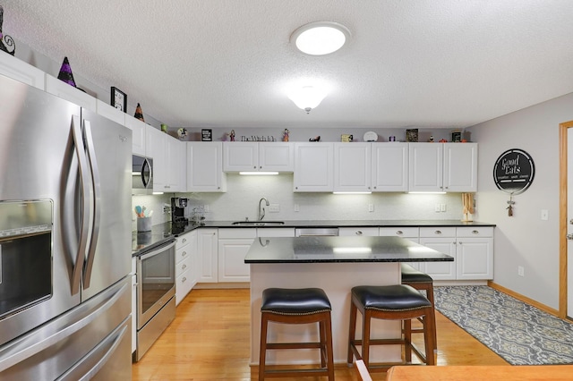 kitchen with a breakfast bar, sink, a center island, appliances with stainless steel finishes, and white cabinets