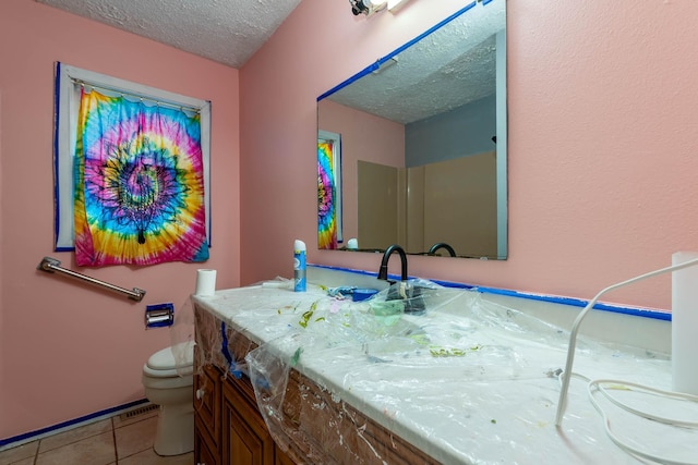 bathroom featuring tile patterned floors, vanity, toilet, and a textured ceiling