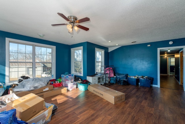 living room featuring ceiling fan, dark wood-type flooring, and a textured ceiling