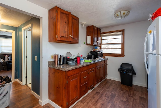 kitchen with white refrigerator, dark wood-type flooring, and a textured ceiling