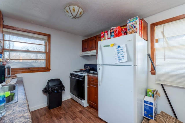 kitchen featuring white refrigerator, dark hardwood / wood-style floors, gas stove, and a textured ceiling