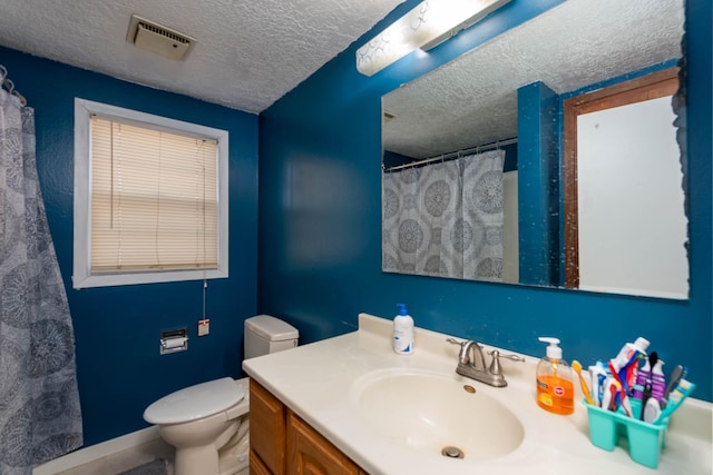 bathroom with vanity, curtained shower, toilet, and a textured ceiling