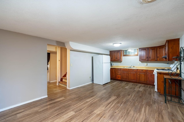 kitchen with dark hardwood / wood-style flooring, sink, a textured ceiling, and white appliances