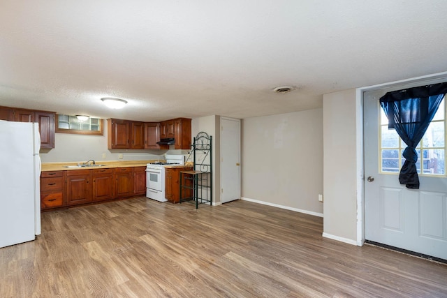 kitchen with sink, white appliances, light hardwood / wood-style flooring, and a textured ceiling