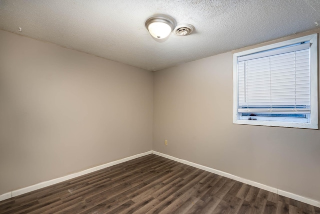 spare room featuring a textured ceiling and dark hardwood / wood-style flooring