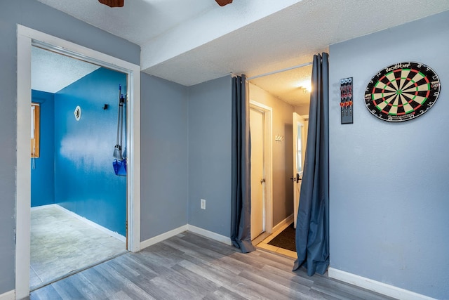 corridor with light hardwood / wood-style flooring and a textured ceiling