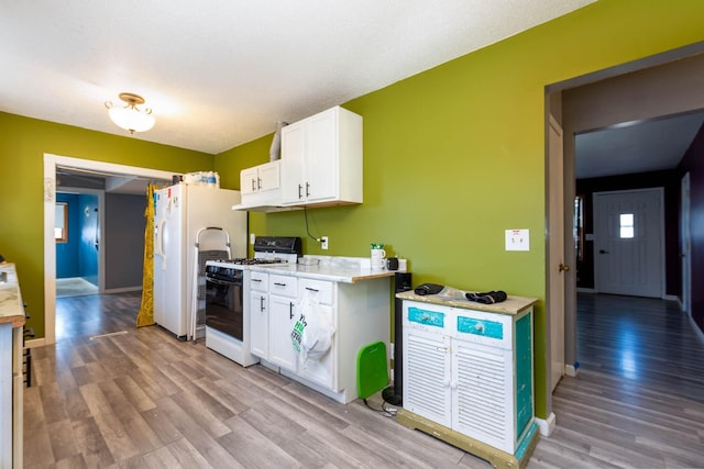 kitchen with white refrigerator, light hardwood / wood-style floors, gas stove, and white cabinets