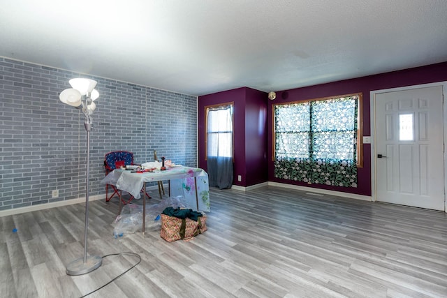 interior space with light hardwood / wood-style floors, a textured ceiling, and brick wall