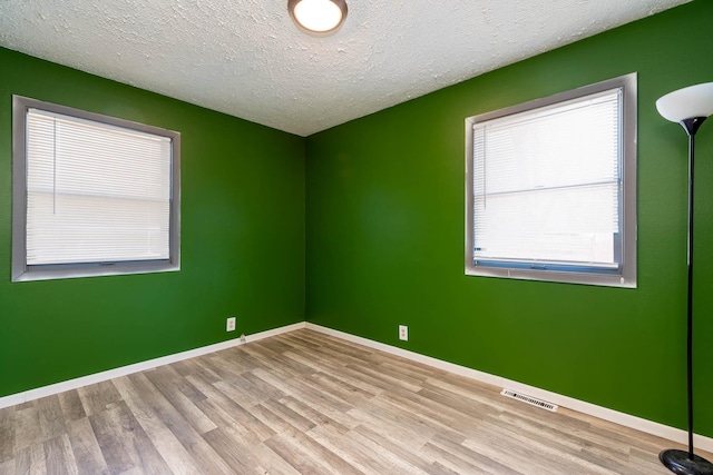 unfurnished room with a textured ceiling and light wood-type flooring