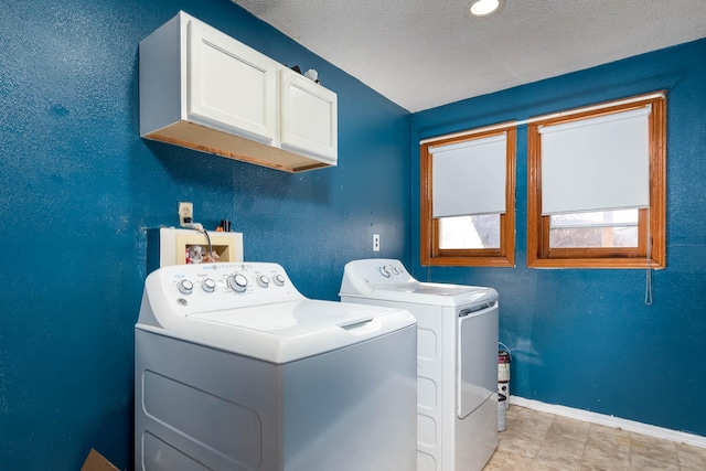 washroom featuring cabinets, a textured ceiling, and washing machine and clothes dryer