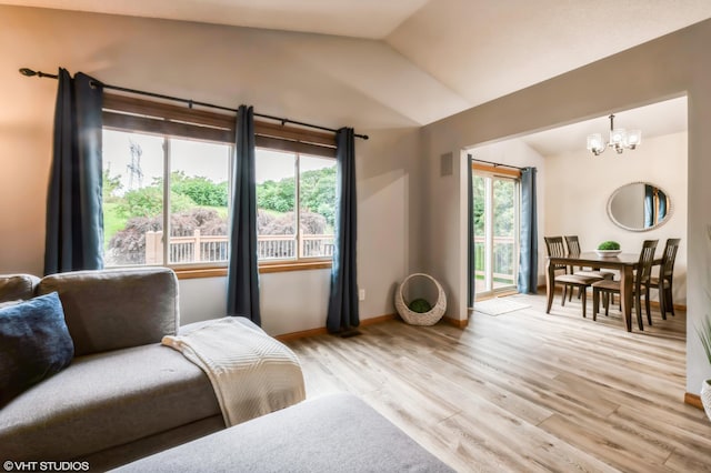 living area featuring lofted ceiling, a chandelier, and light hardwood / wood-style floors