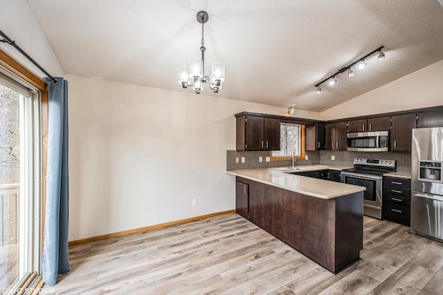 kitchen featuring lofted ceiling, appliances with stainless steel finishes, kitchen peninsula, and hanging light fixtures