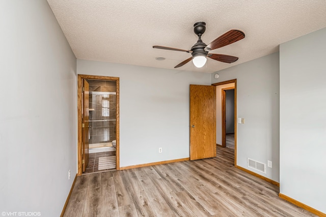 empty room featuring ceiling fan, light hardwood / wood-style floors, and a textured ceiling