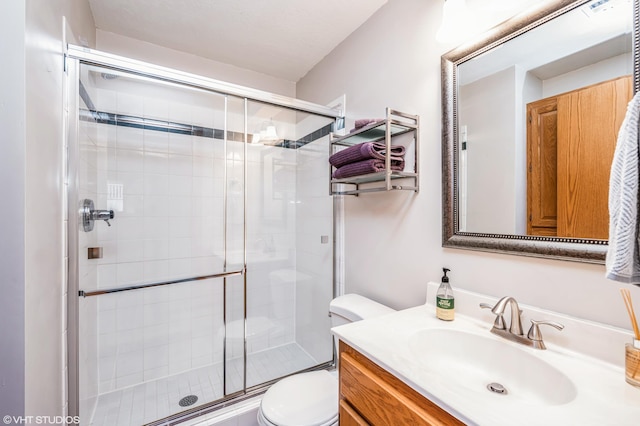 bathroom featuring vanity, toilet, and a shower with door