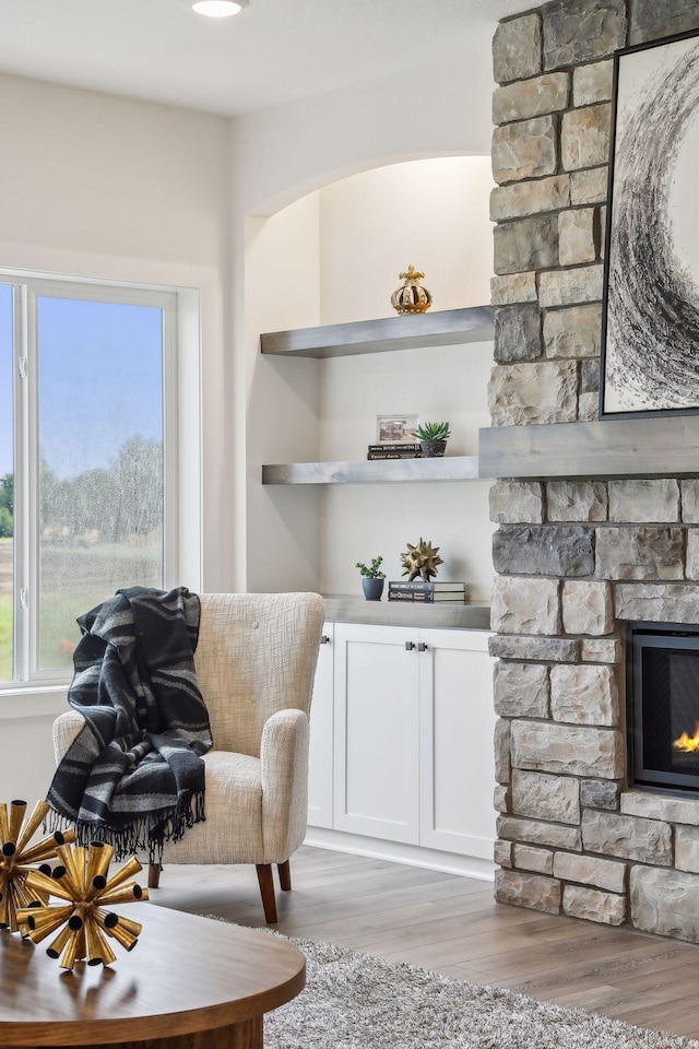 sitting room featuring a stone fireplace and light wood-type flooring