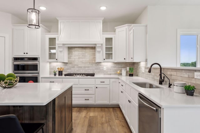 kitchen with appliances with stainless steel finishes, sink, hanging light fixtures, and white cabinets