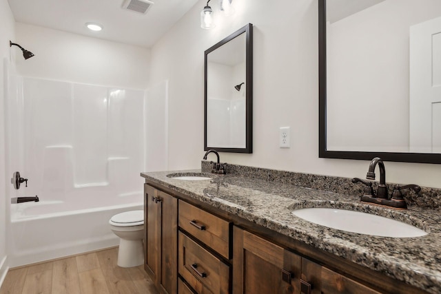 full bathroom with hardwood / wood-style flooring, vanity, tub / shower combination, and toilet