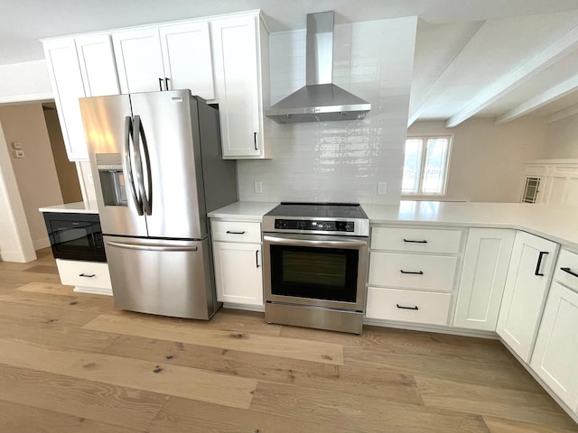 kitchen with white cabinetry, stainless steel appliances, light hardwood / wood-style floors, and wall chimney range hood