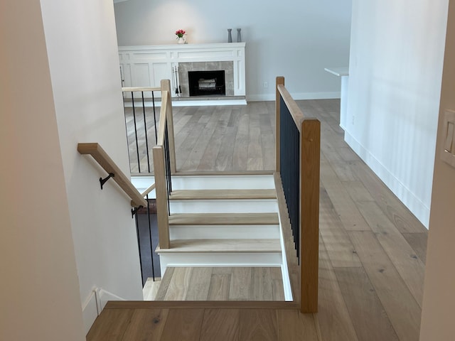 stairway with a tiled fireplace and hardwood / wood-style flooring