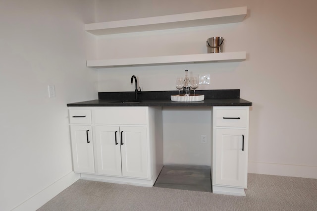 bar featuring white cabinetry, sink, and light colored carpet