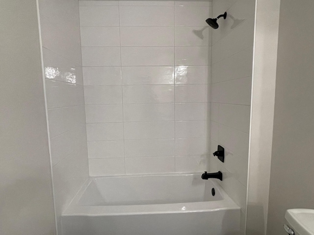 bathroom featuring toilet and tiled shower / bath combo