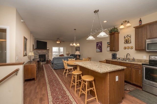 kitchen featuring sink, a kitchen bar, a center island, light stone counters, and stainless steel appliances