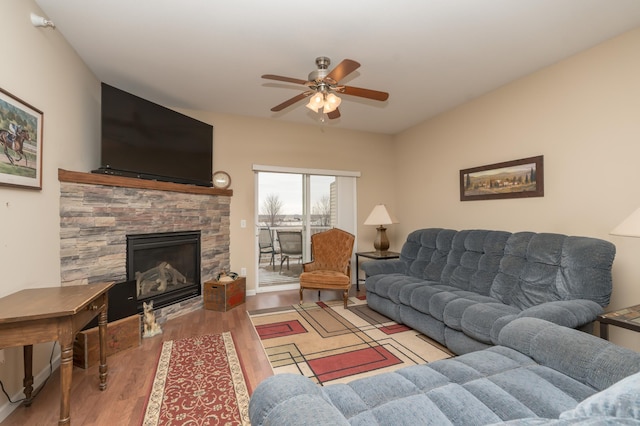 living room featuring a stone fireplace, hardwood / wood-style floors, and ceiling fan