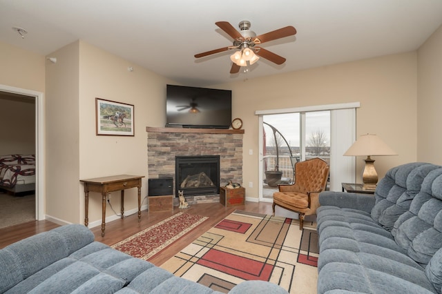 living room with a stone fireplace, hardwood / wood-style floors, and ceiling fan