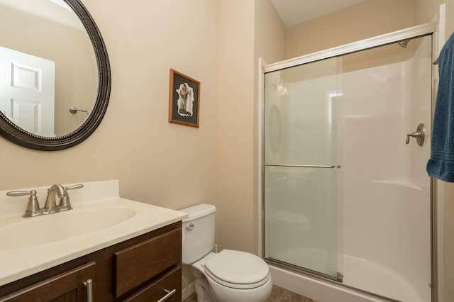 bathroom featuring vanity, a shower with door, and toilet